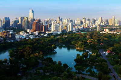 Trees and buildings in city against sky