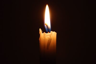 Close-up of lit candle in dark room