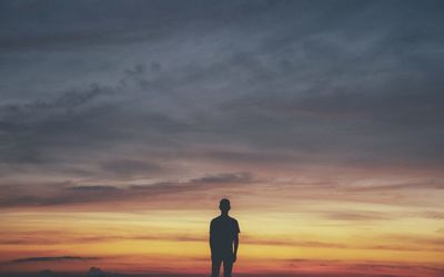 Silhouette man standing against cloudy sky during sunset