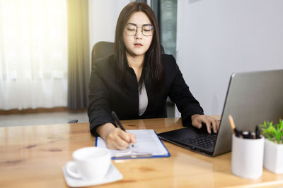 Young woman using mobile phone while sitting on table