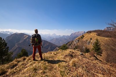 Rear view of man standing on mountain against sky