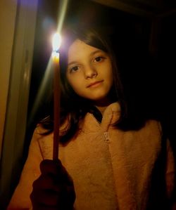Portrait of young woman holding lit candle