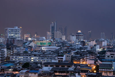 Illuminated buildings in city against clear sky at night