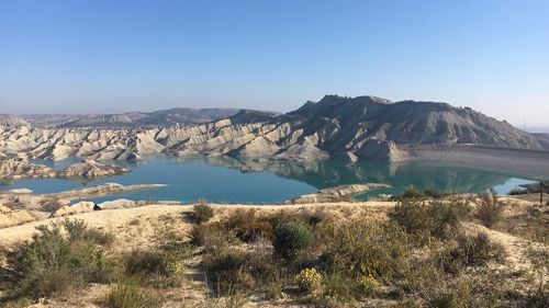 Scenic view of lake and mountains against clear blue sky