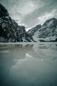 Scenic view of lake by snowcapped mountains against sky