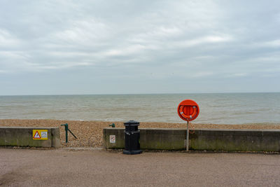 Information sign on beach against sky