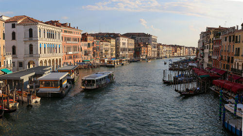 Canal amidst buildings in city against sky