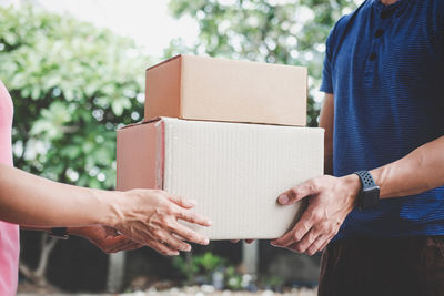 Midsection of couple holding cardboard boxes