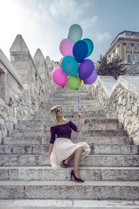 Happy young woman holding balloons at historic place
