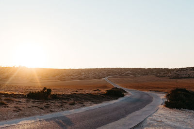 Road passing through desert against clear sky