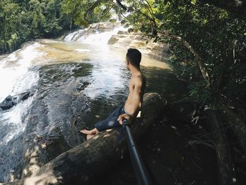 High angle view of shirtless woman sitting in water