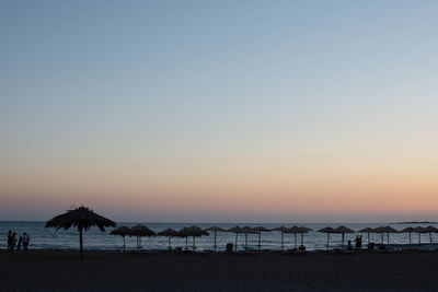 Scenic view of beach against clear sky during sunset