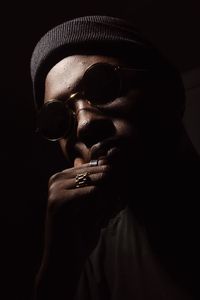 Close-up portrait of man wearing sunglasses in darkroom