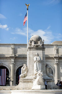 American flag and statue against historic building in city