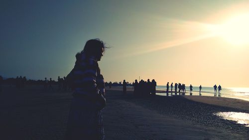 Silhouette people on beach against sky during sunset