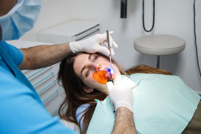 Midsection of male dentist treating female patient in clinic