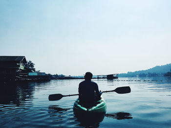 Rear view of man in boat against sky