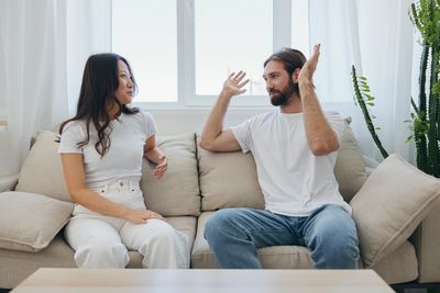 Friends using phone while sitting on sofa at home