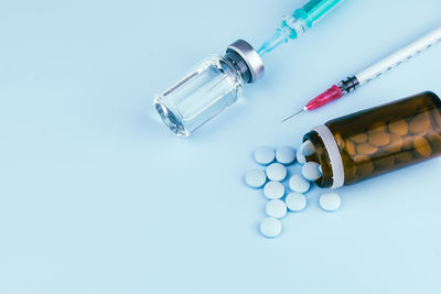 Close-up of pills spilling from bottle against blue background
