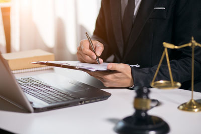 Midsection of man holding paper with text on table