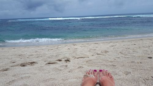 Low section of woman on beach against sky