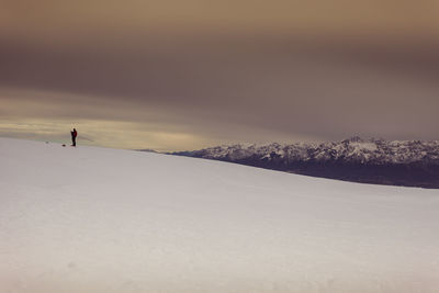 Person standing on snow covered land against sky