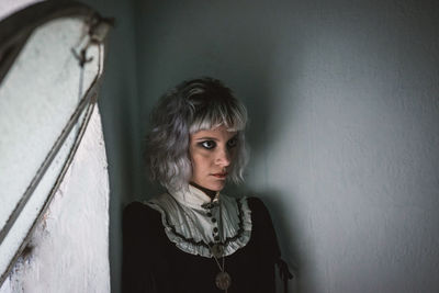 Thoughtful woman with dyed hair by wall