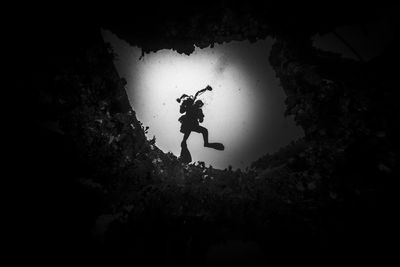 Silhouette scuba diver swimming underwater