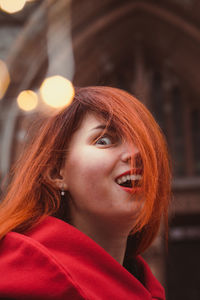 Close up excited young woman in red coat in city portrait picture