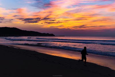 Silhouette man standing on beach against sky during sunset