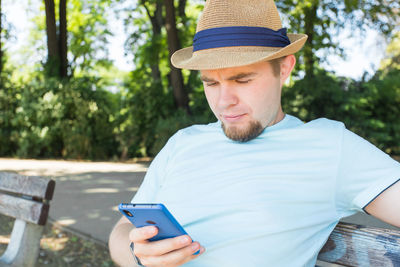 Man wearing hat using mobile phone outdoors