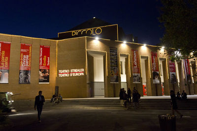 People walking on illuminated street at night