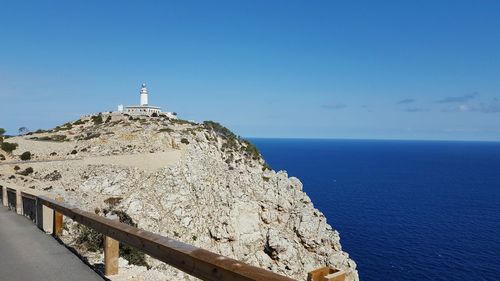 Cliff by blue sea against sky