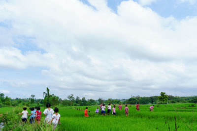 People walking on field against sky