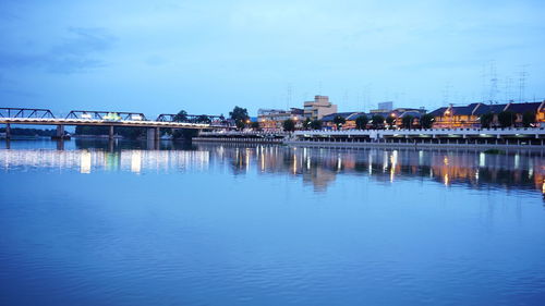 Reflection of illuminated buildings in river against sky