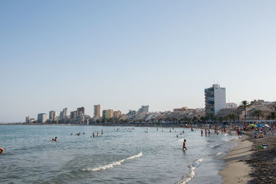 People in sea against clear sky