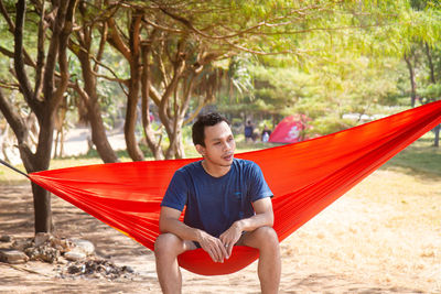 Young happy asian man relaxing lying in hammock person