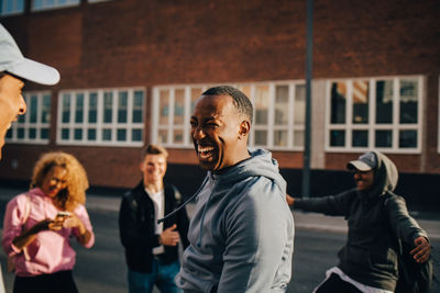 Cheerful young man dancing with friends in city on sunny day