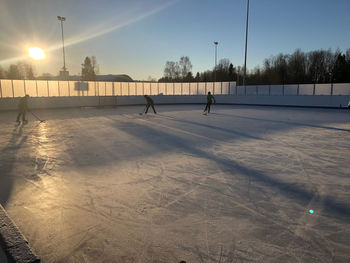 People playing ice hockey during sunset