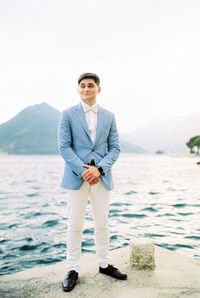 Portrait of businessman standing against sea