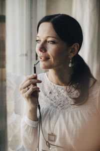 Creative businesswoman talking through earphones by window in office