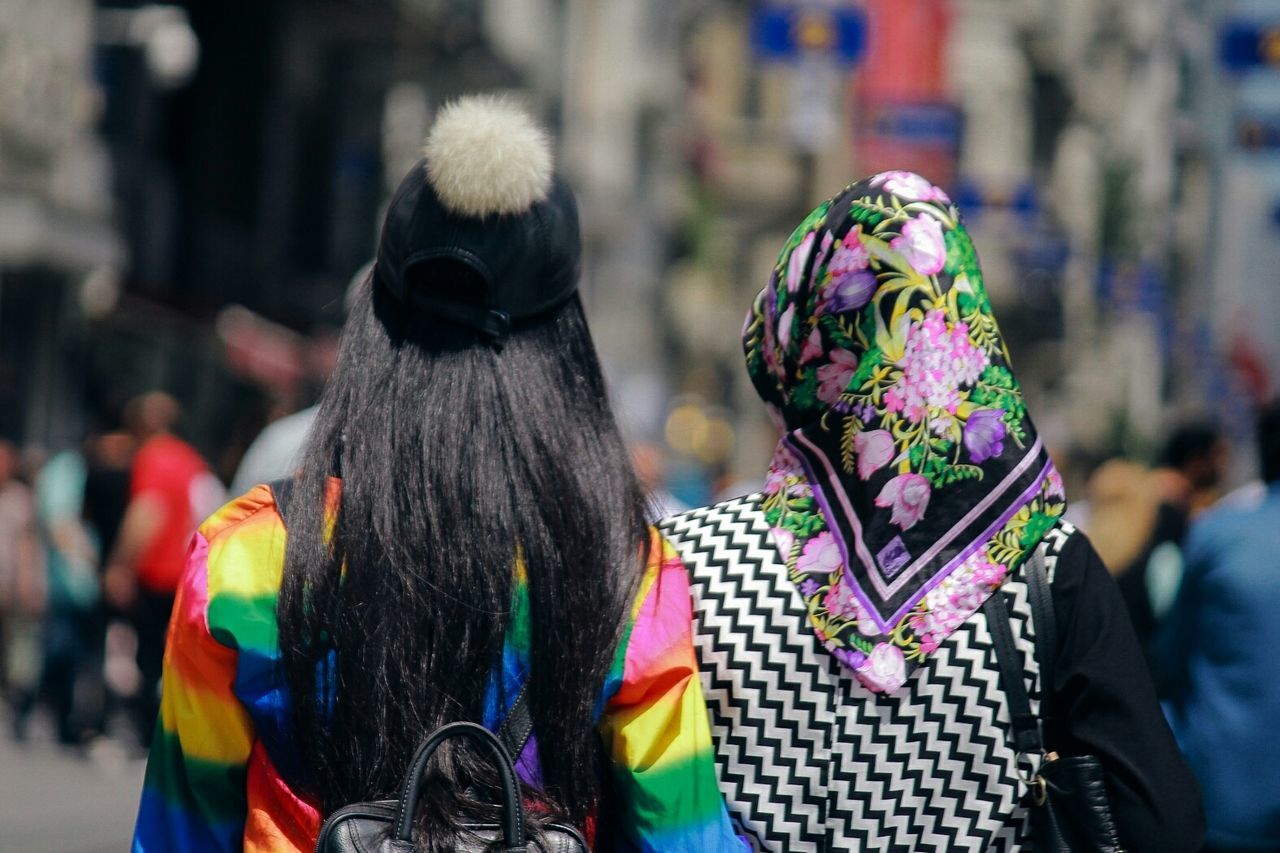 rear view, real people, focus on foreground, incidental people, street, lifestyles, people, clothing, group of people, adult, leisure activity, day, multi colored, women, city, outdoors, men, waist up, casual clothing, hairstyle, human hair, warm clothing