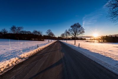 Snow covered landscape against blue sky