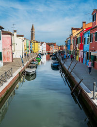 Canal amidst buildings in city against sky