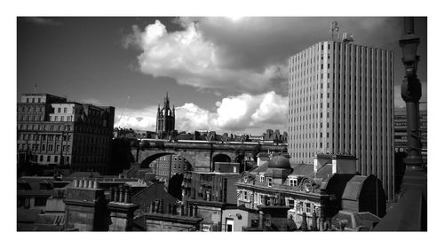 Buildings against cloudy sky on sunny day in city