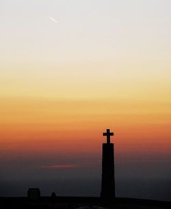 Silhouette of bell tower against orange sky