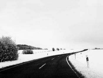 Road amidst snow covered trees against sky