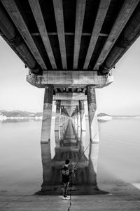 Man standing on bridge over river against sky