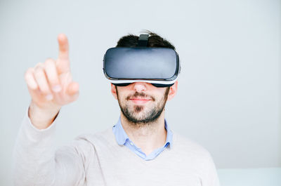 Portrait of man wearing virtual reality glasses against white background
