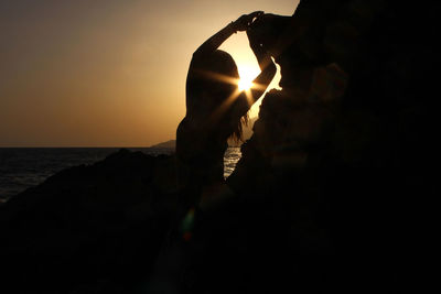 Silhouette woman at beach against sky during sunset